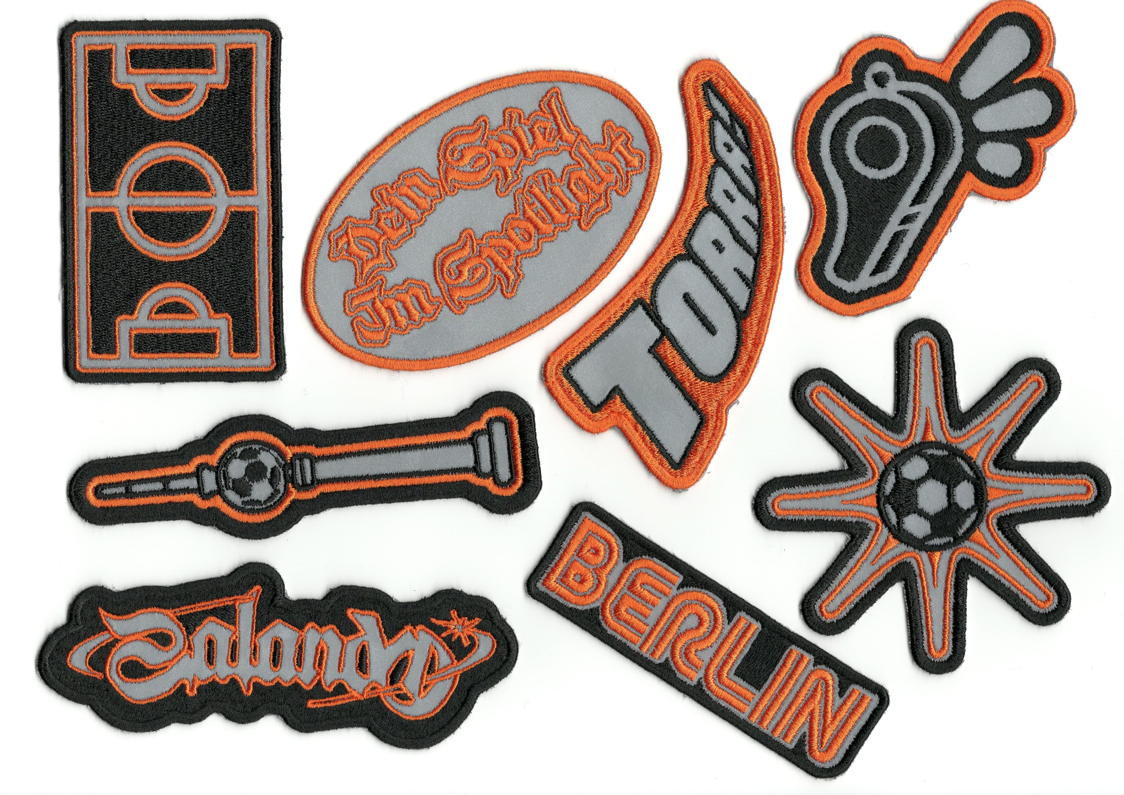 Orange, grey and black patch designs featuring a pitch, whistle, football and campaign lettering