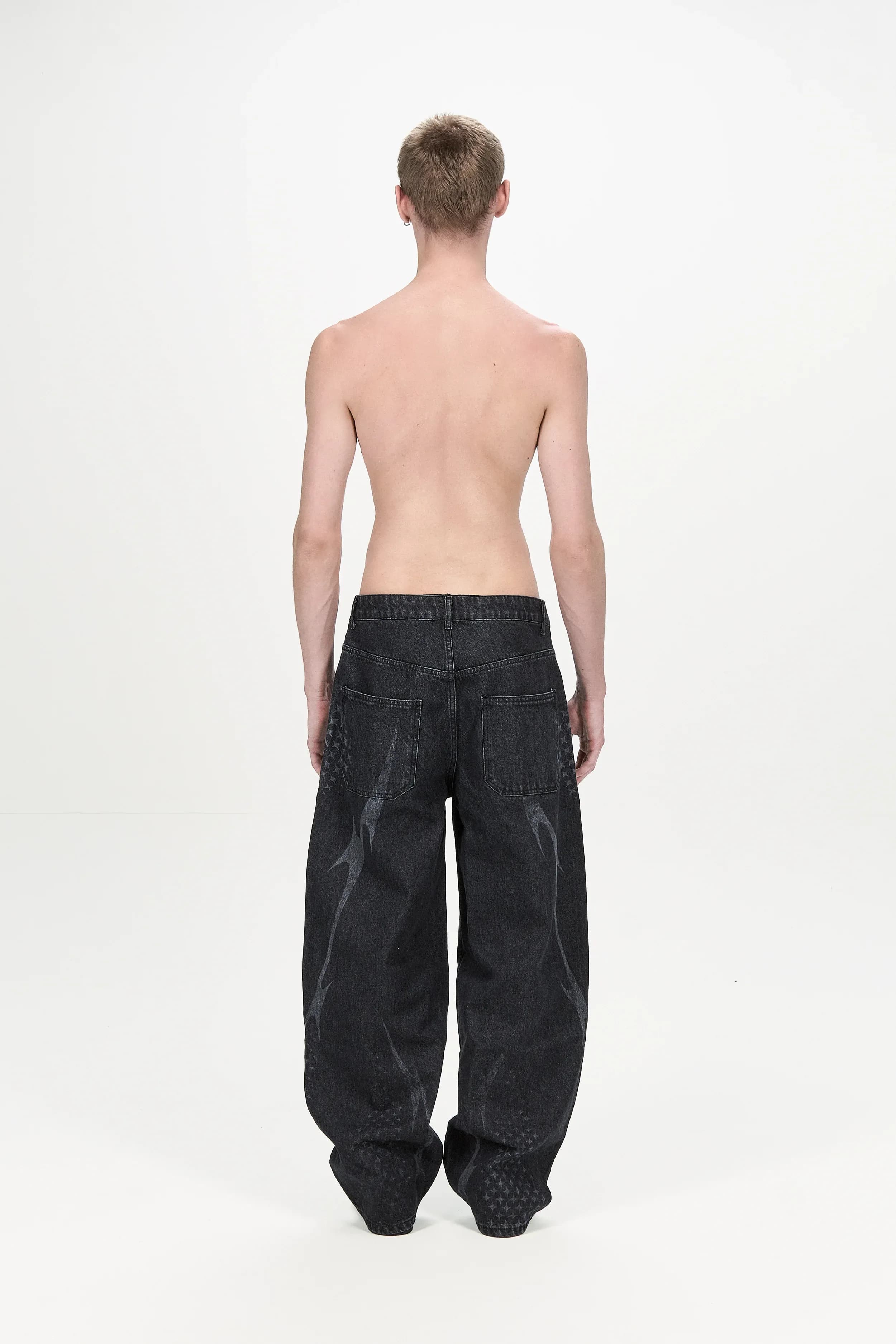 Rear view of dark jeans with curved graphics along the legs