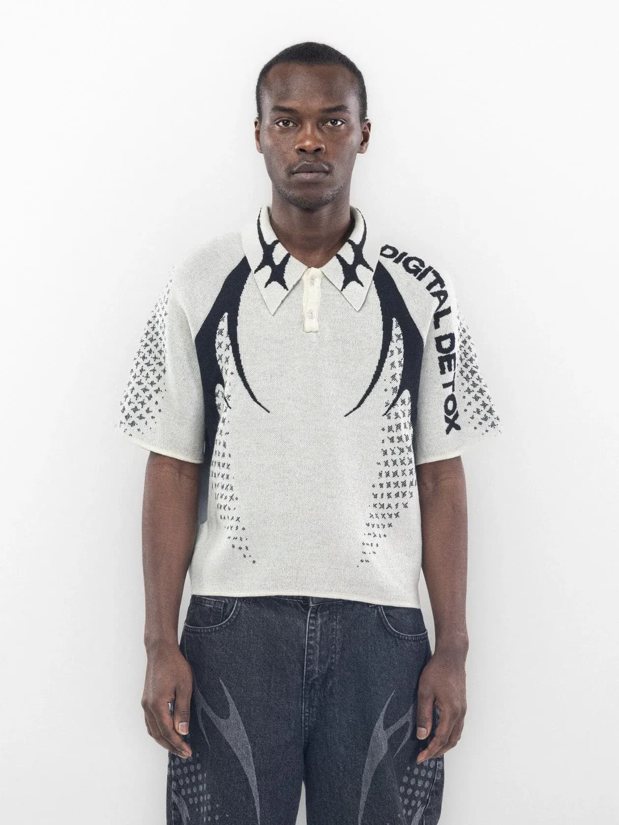 Front of a white polo with black shoulder graphics, lettering and patterned sleeves