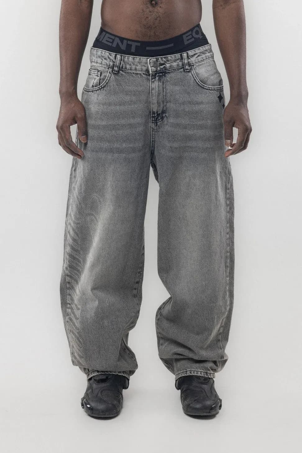 Front view of loose grey jeans with a dark branded waistband
