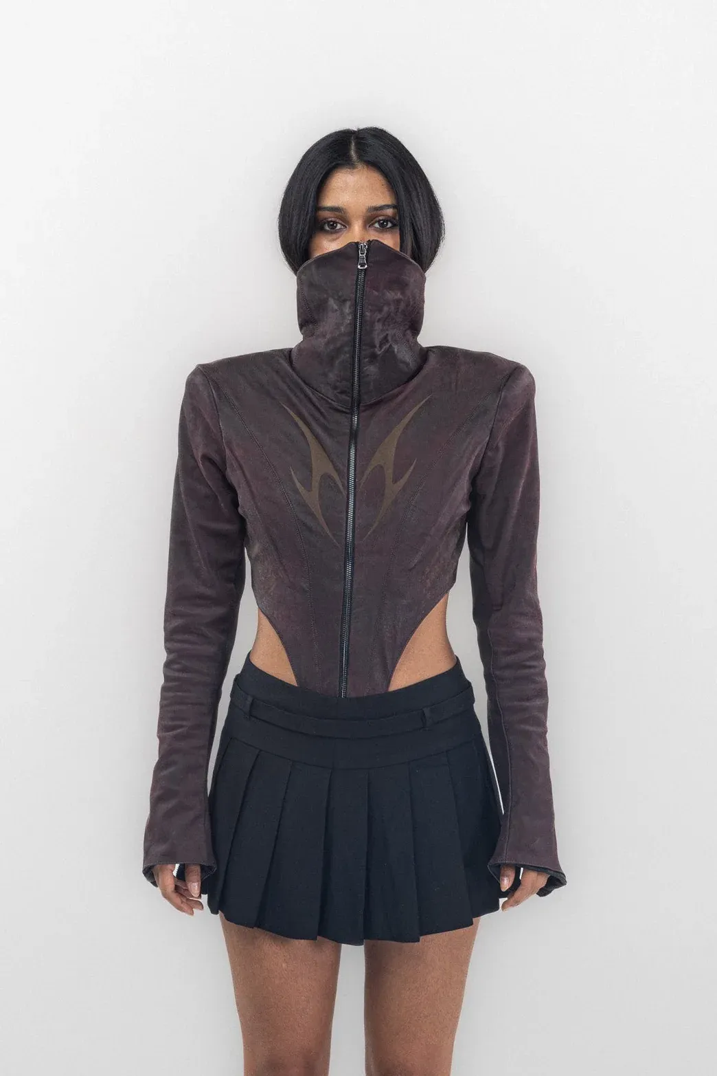 Front of a burgundy high collar bodysuit with side cutouts, worn with a pleated skirt