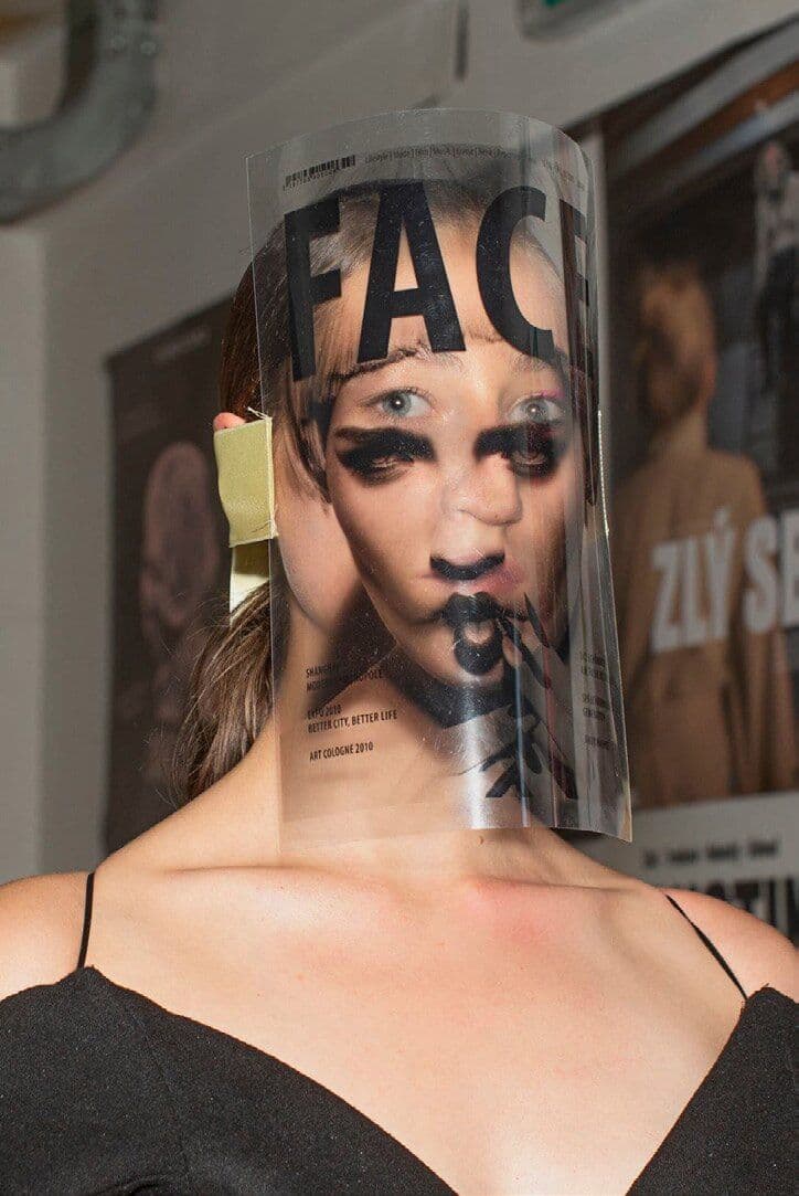Portrait with bold black lettering across a transparent cylindrical face covering