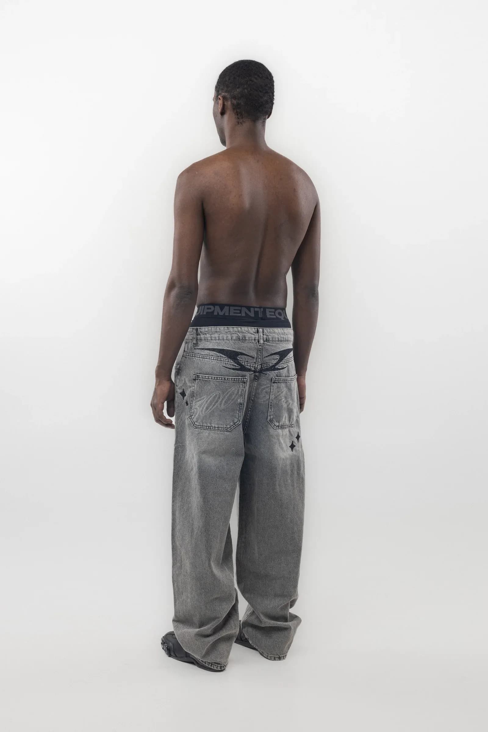 Rear view of loose grey jeans with a dark waistband