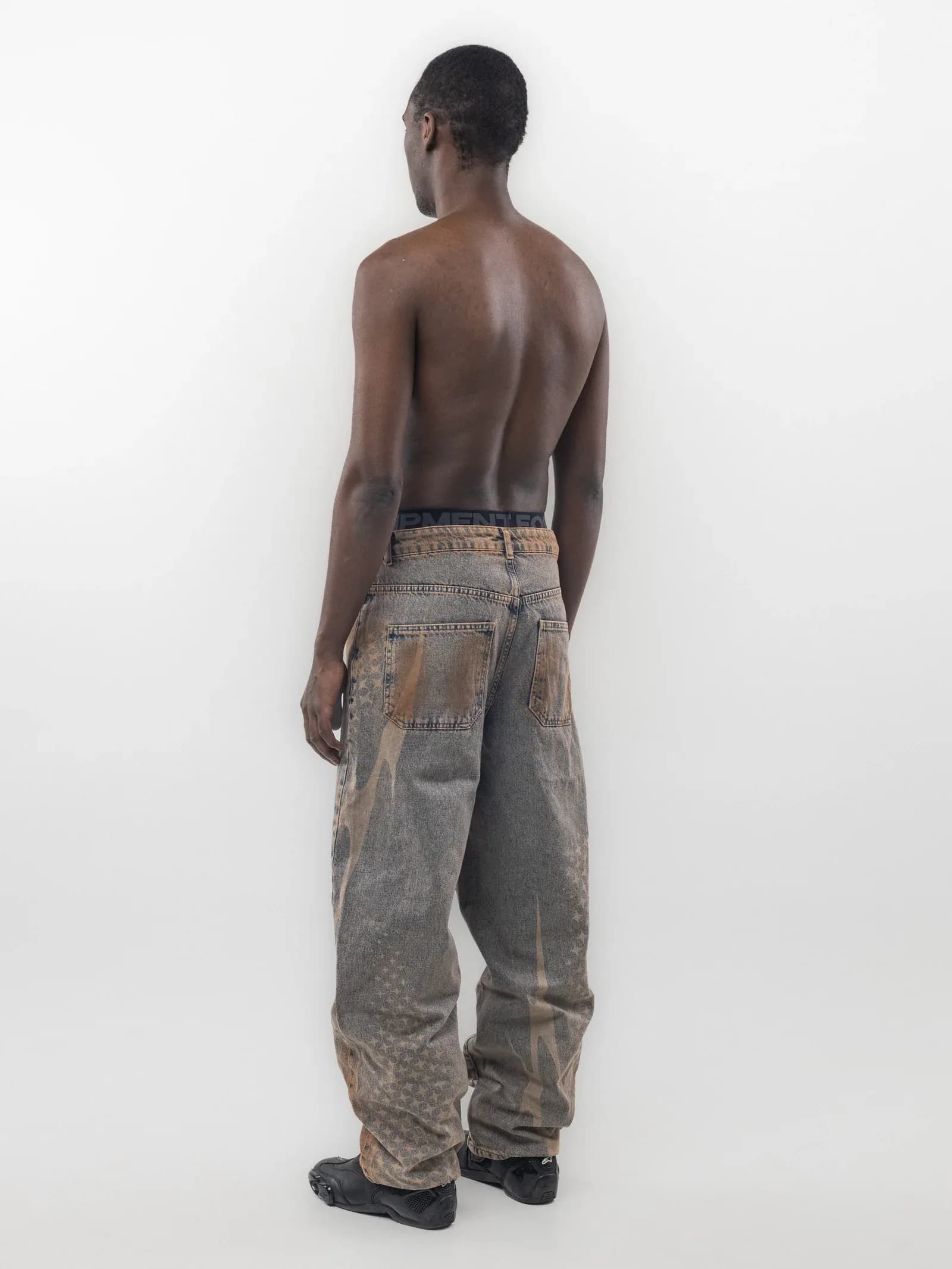 Rear view of grey wide leg jeans with pale graphics along the legs
