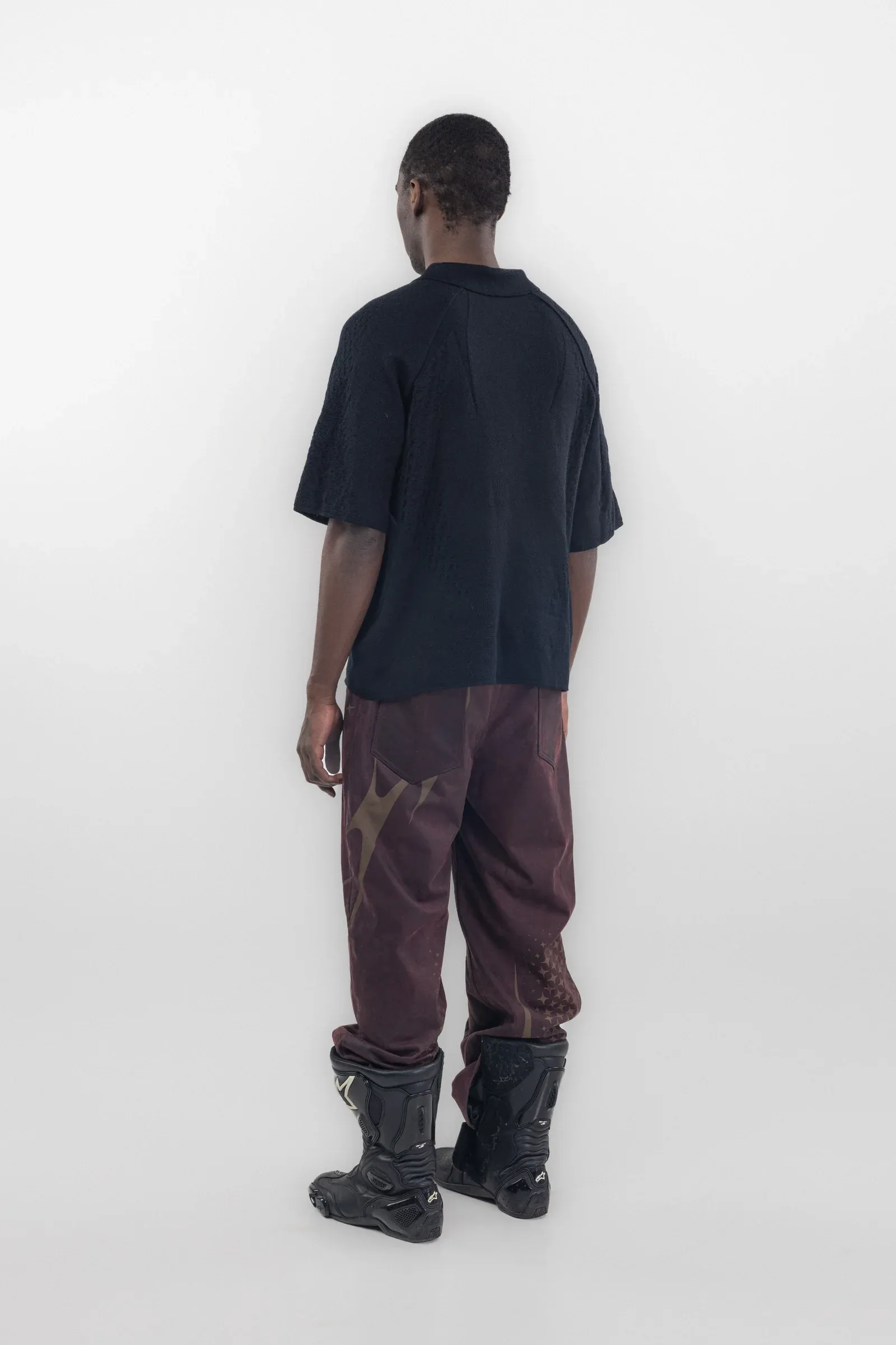 Rear view of a dark polo worn with burgundy trousers