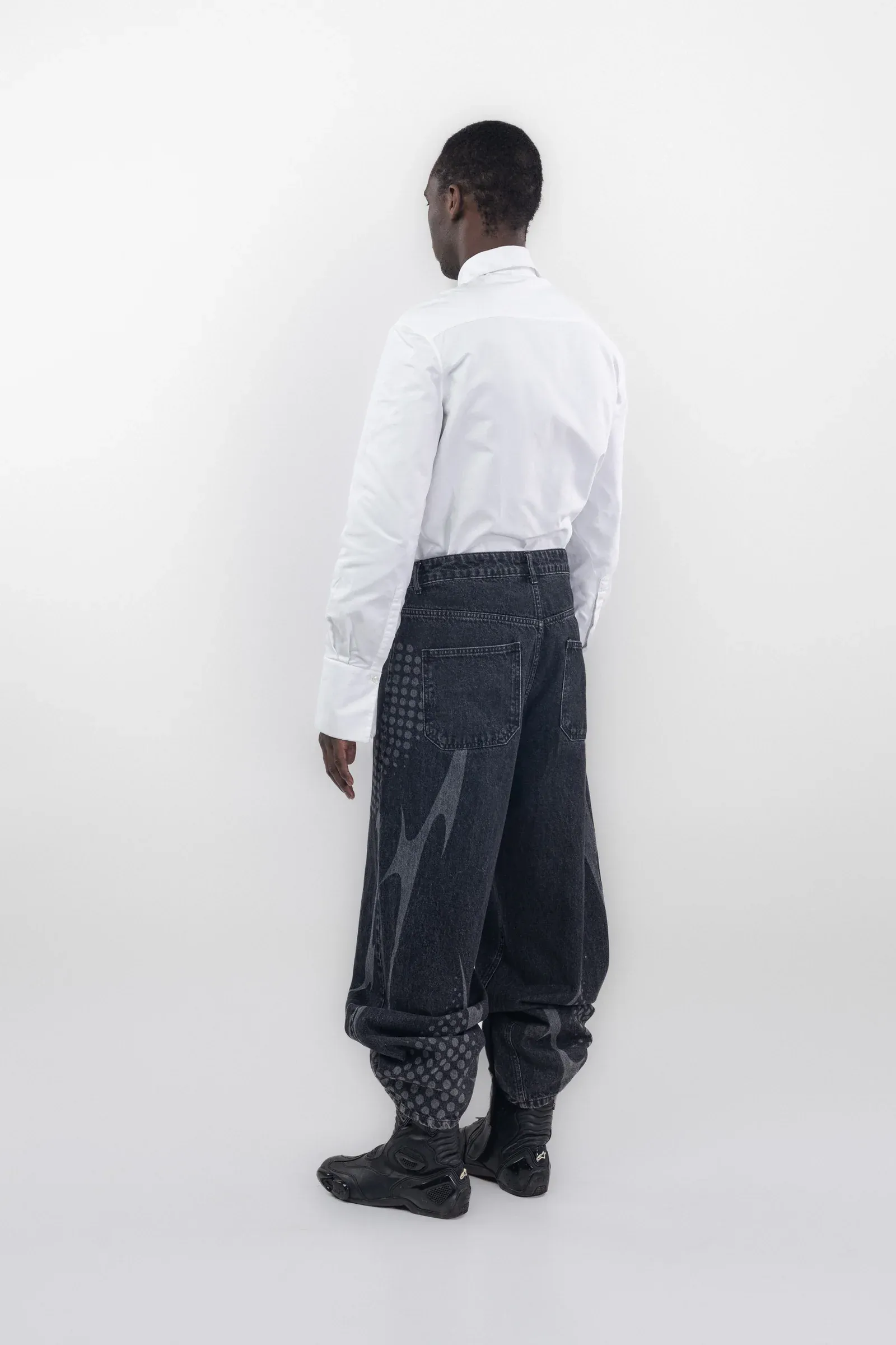 Rear view of dark wide leg jeans with pale graphics along the legs