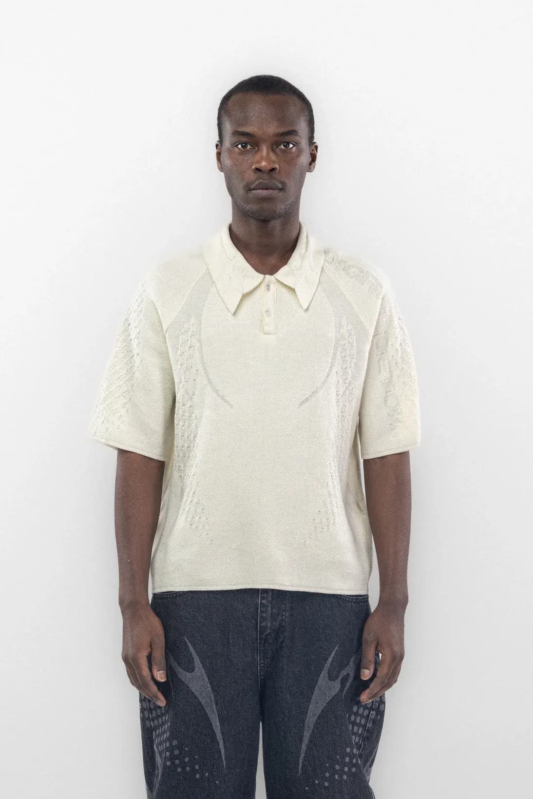 Front of a cream polo with faint curved chest graphics and textured sleeves