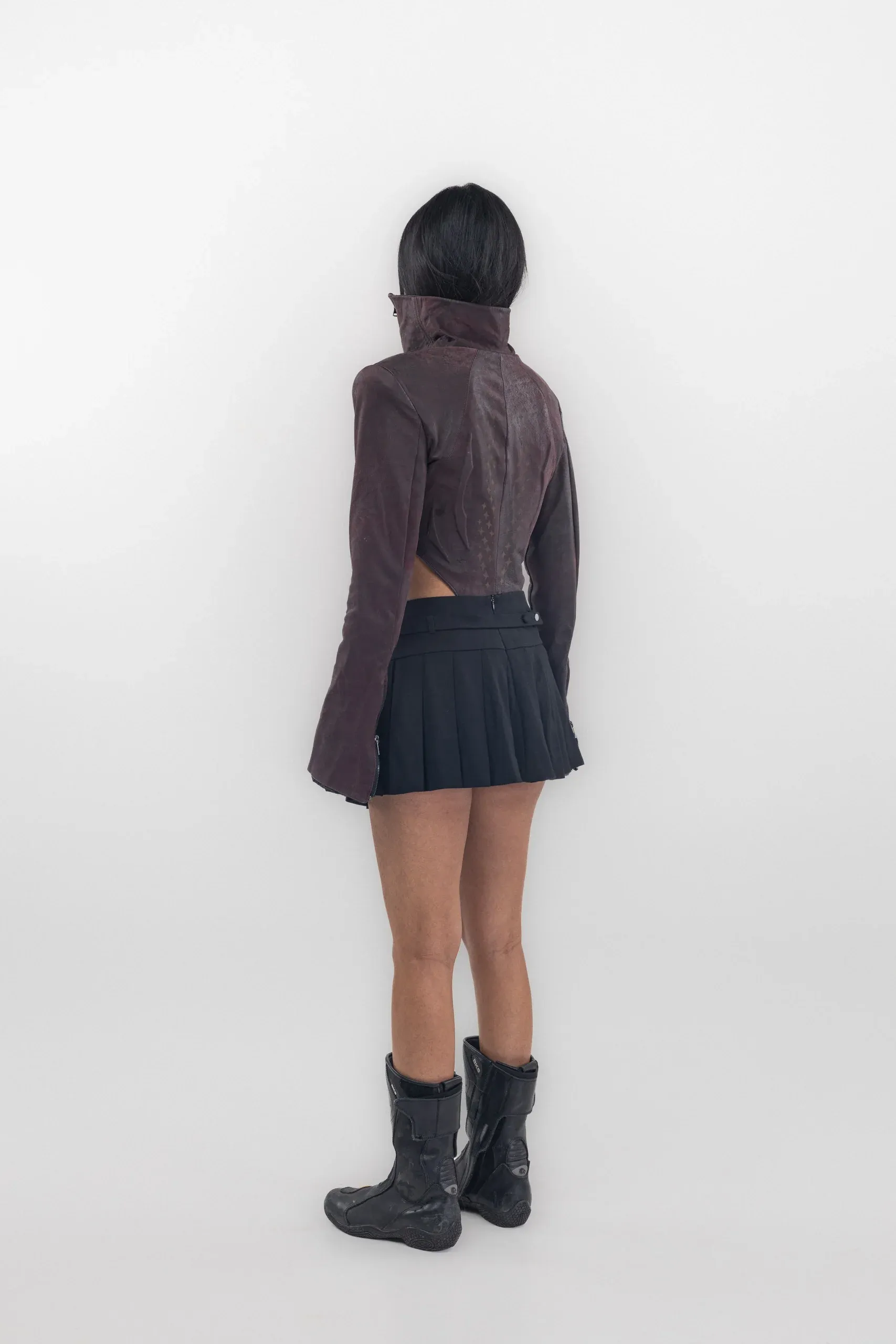 Rear of a burgundy high collar bodysuit and dark pleated skirt