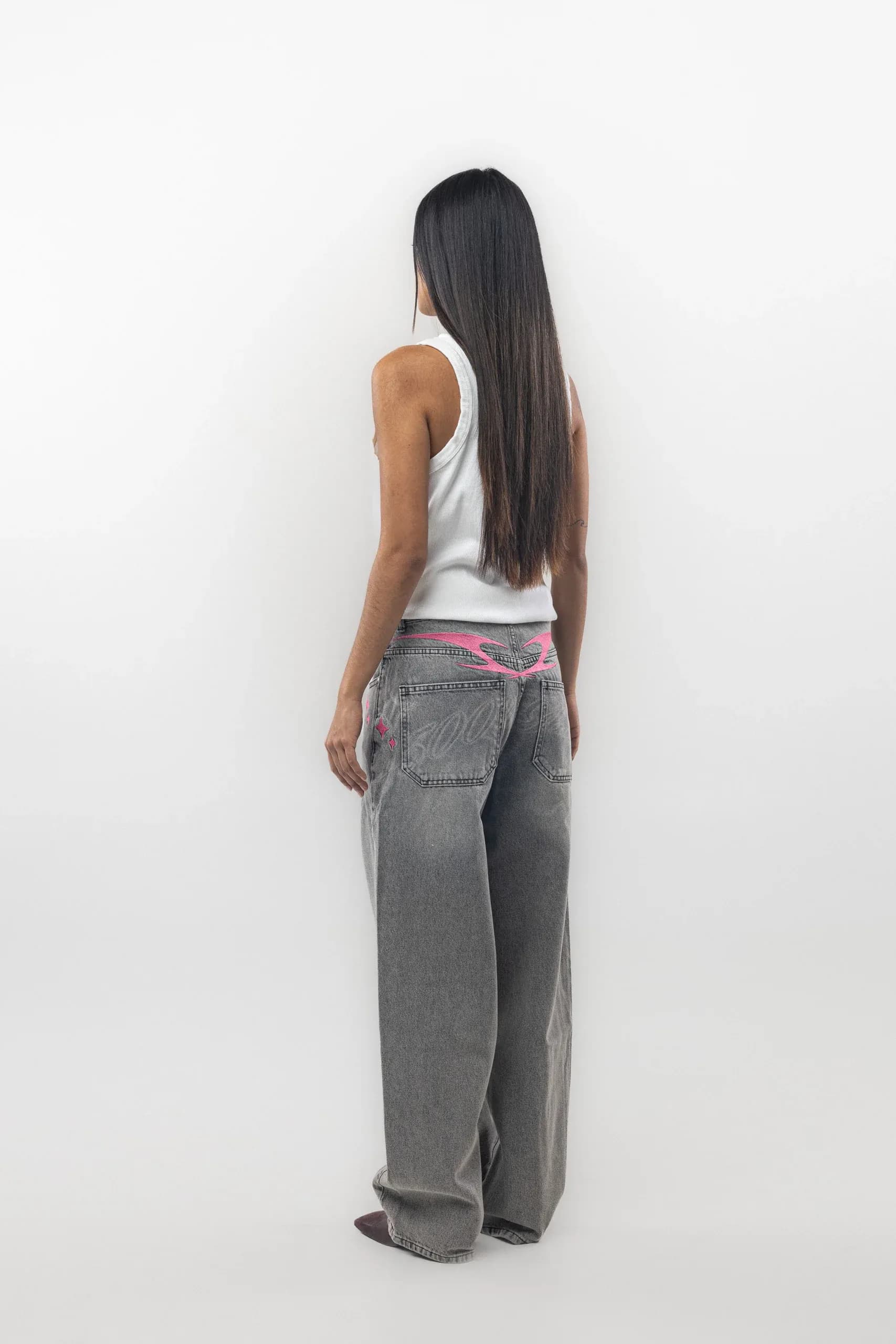 Rear view of grey jeans with a bright pink waistband detail
