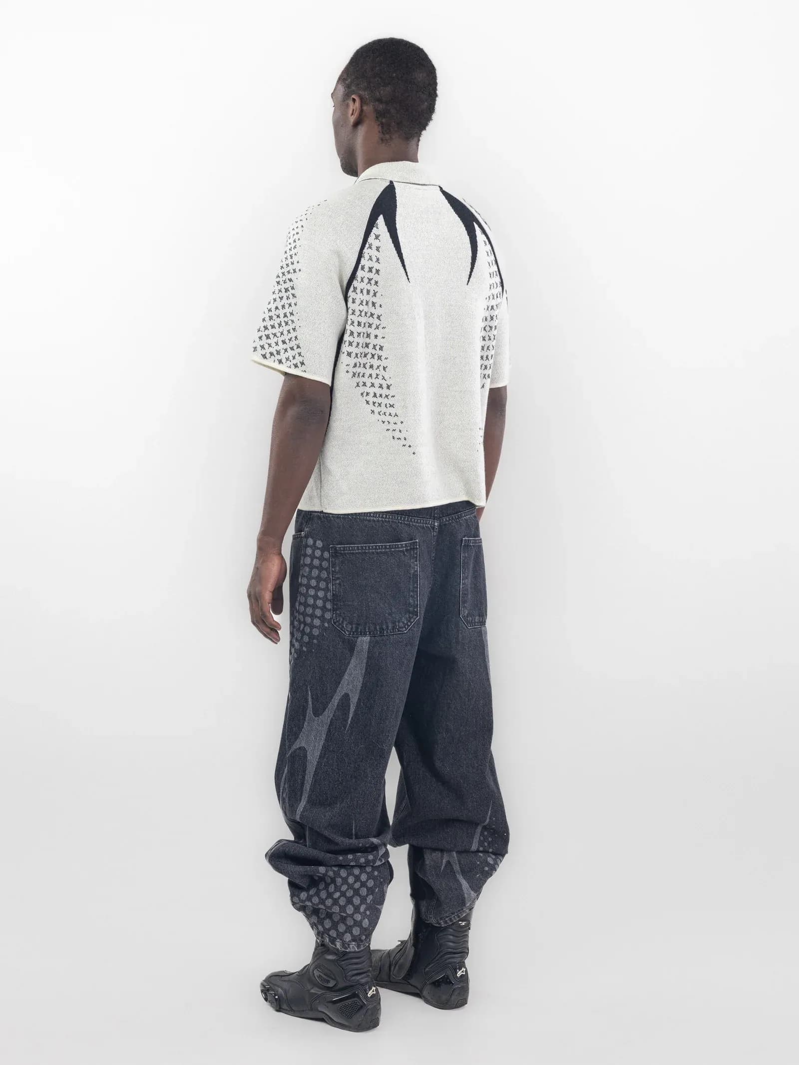 Rear of a white polo with black curved shoulder graphics and patterned sleeves