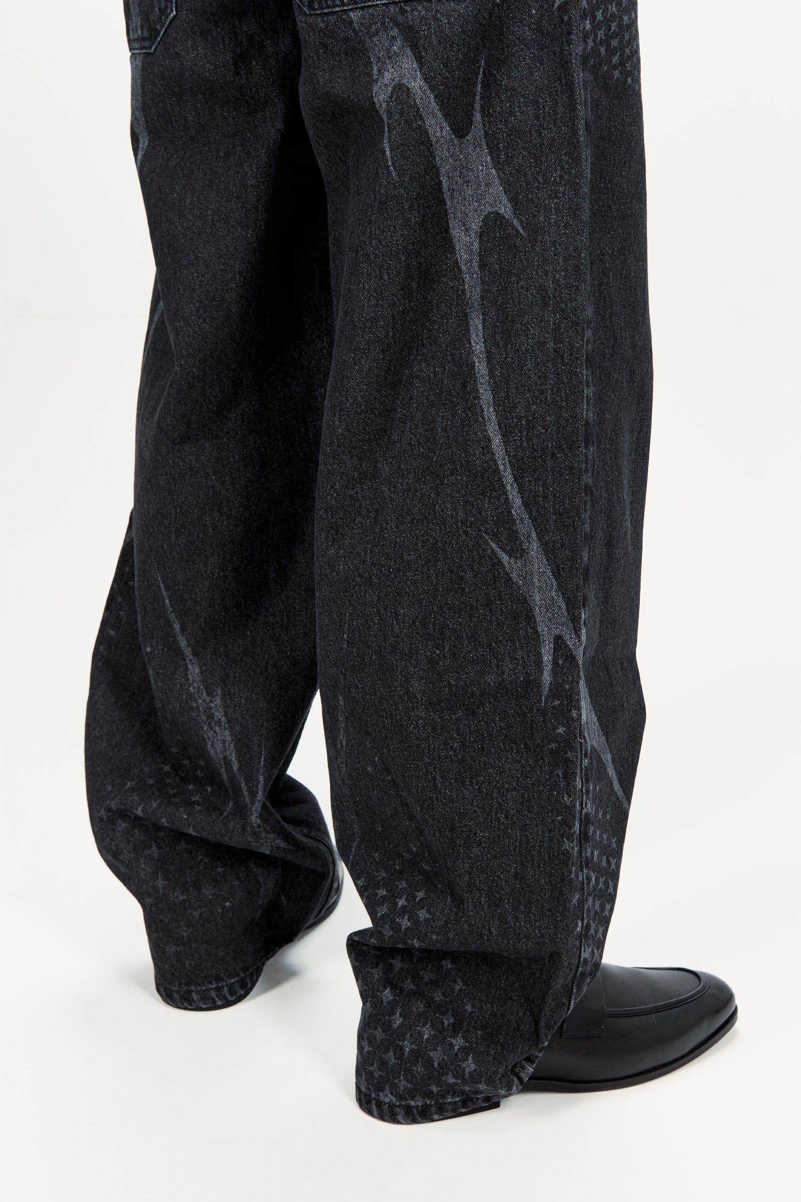 Close view of dark jeans with a pale flame shape and patterned lower leg panel