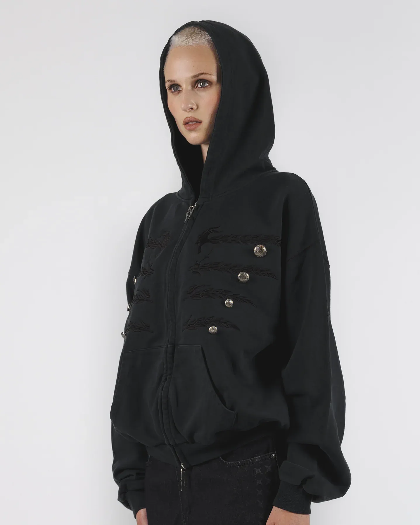 Side view of a black hooded zip jacket with buttoned chest details